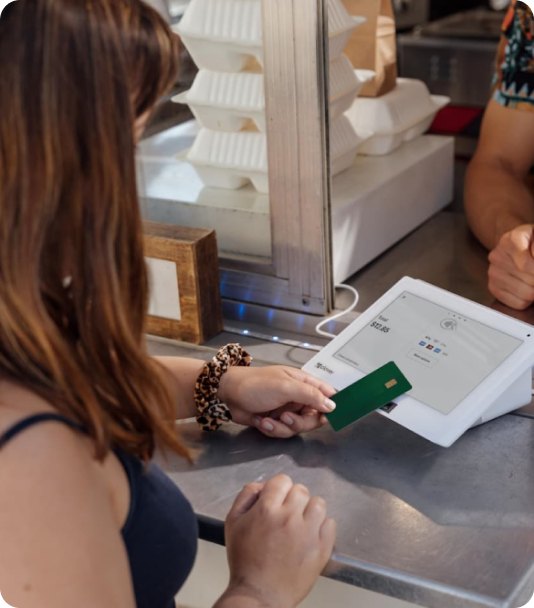 Customer tapping a card on a Paycue POS terminal at a takeaway counter